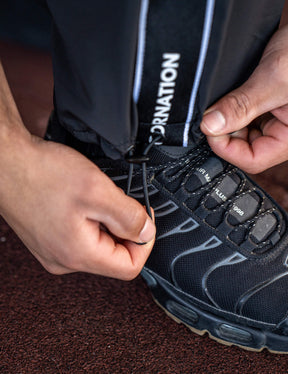 Close up of a GORNATION athlete wearing the GORNATION tracksuite pants in black
