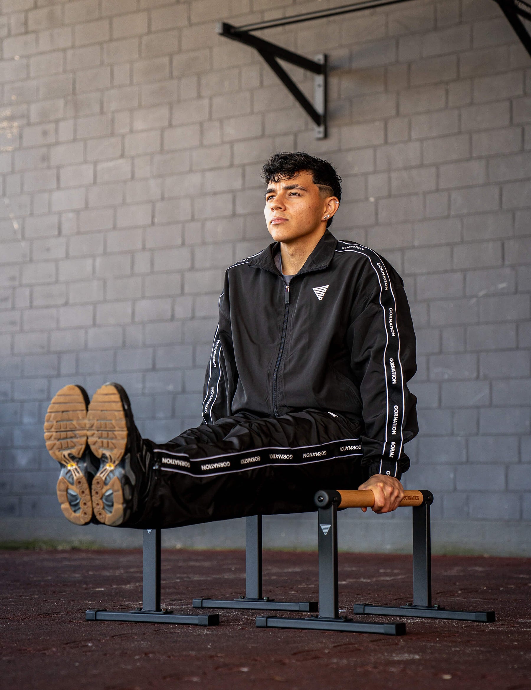 GORNATION athlete doing a L-Sit on GORNATION parallettes wearing a tracksuite