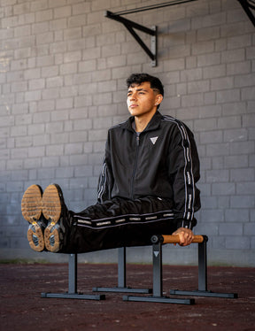 GORNATION athlete doing a L-Sit on GORNATION parallettes wearing a tracksuite