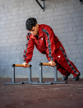 GORNATION athlete doing push ups on GORNATION parallettes wearing a tracksuite